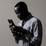 african man using mobile phone with eye strain